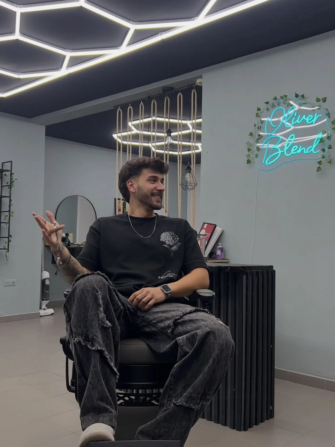 Barbeiro na OliverBlend Studio junto ao letreiro neon
